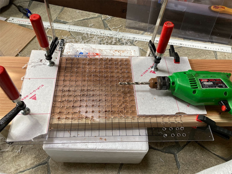 クランプで固定した塩ビ板に穴を開けている様子