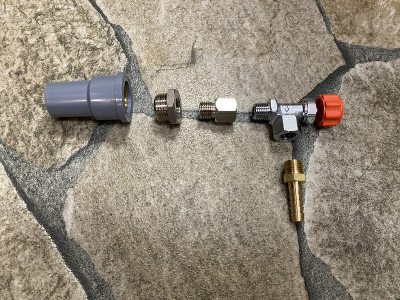 金属製のニードルバルブを塩ビ管と接続するための材料を並べた様子